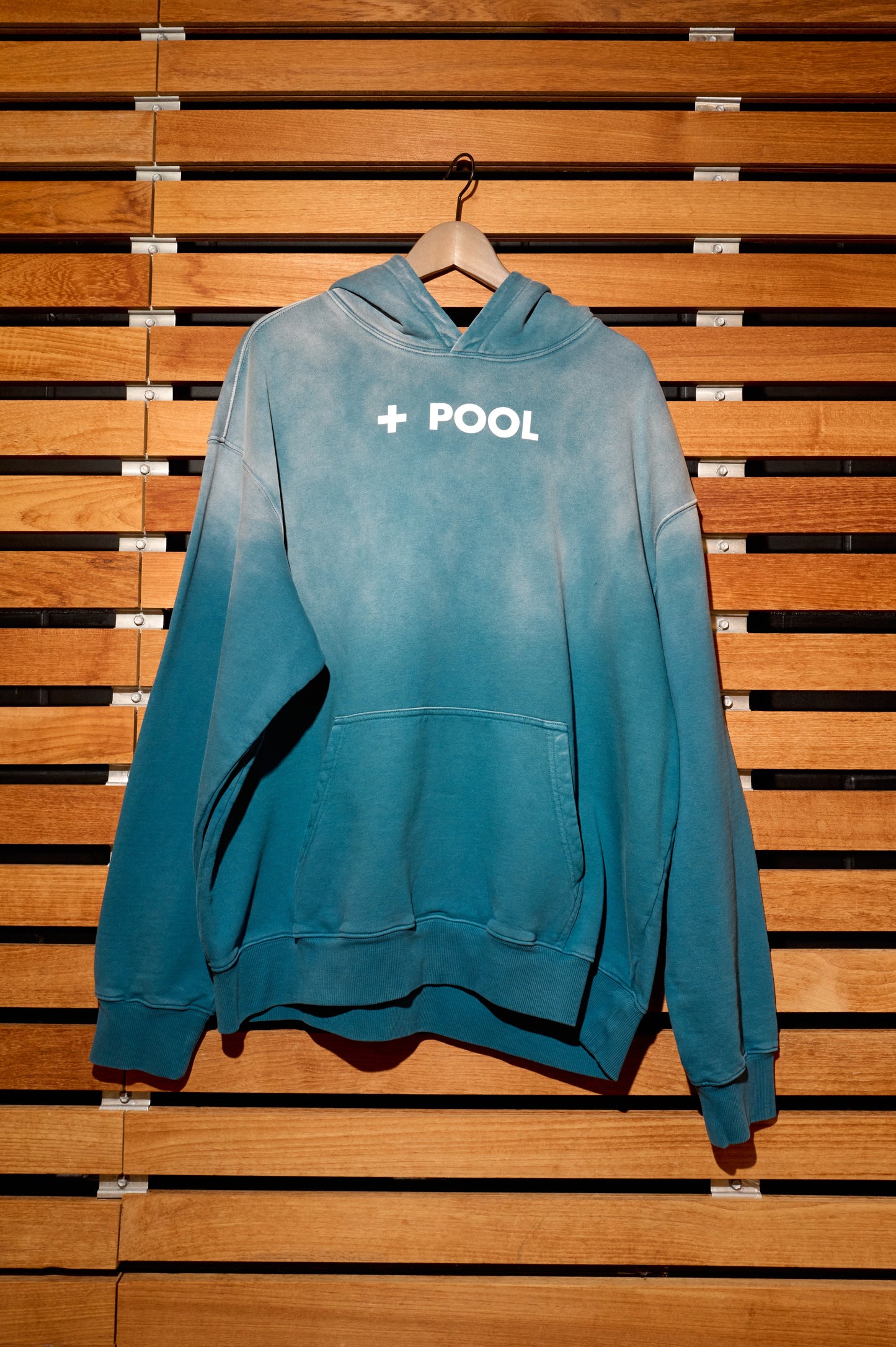A blue hoodie on a wooden wall.
